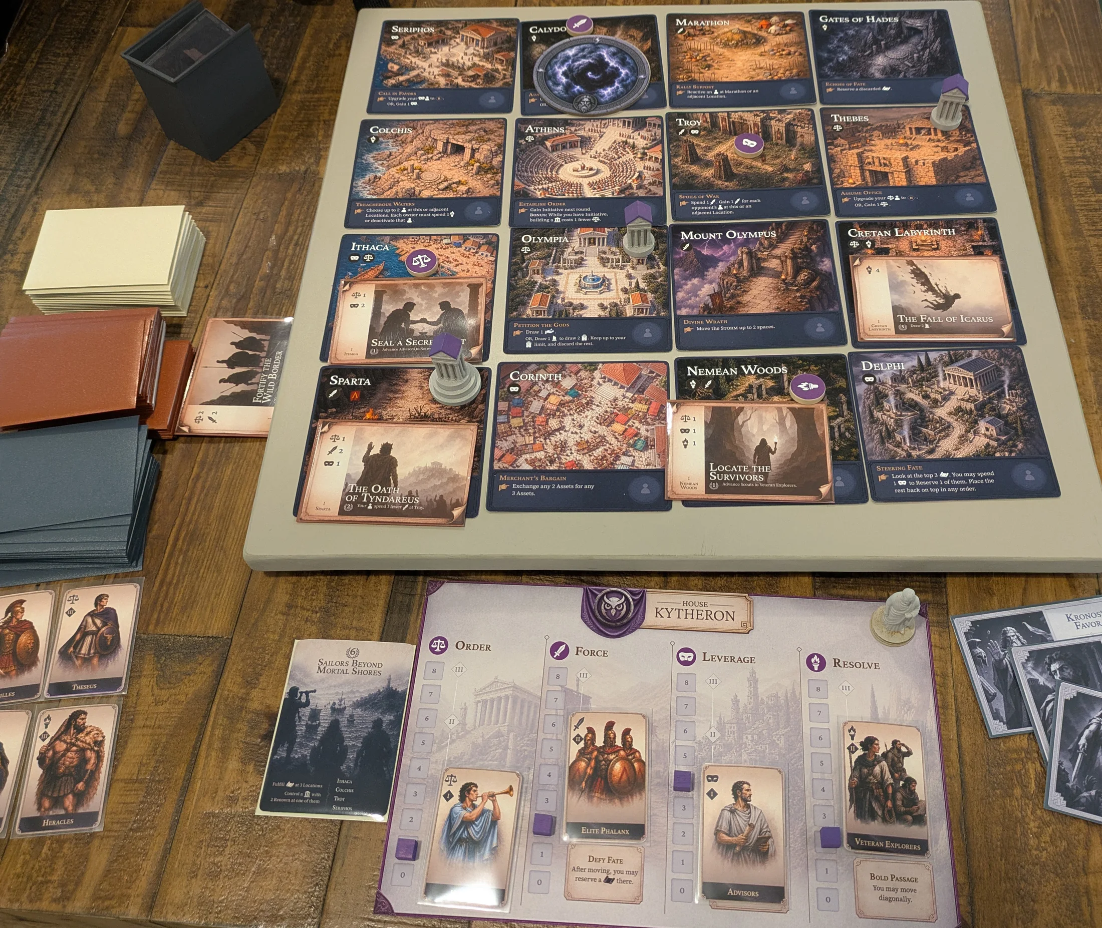 Makers of Mythos prototype set up on a table, showing the modular map, player board, cards, temples, and tokens.